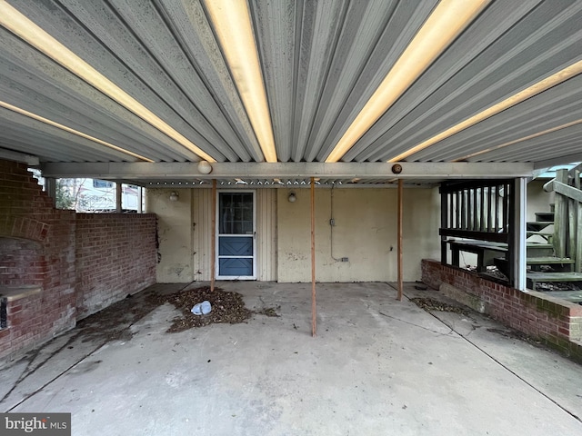 misc room featuring brick wall and unfinished concrete flooring