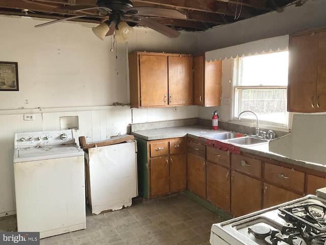 kitchen with a sink, washer / clothes dryer, white range with gas stovetop, and brown cabinets