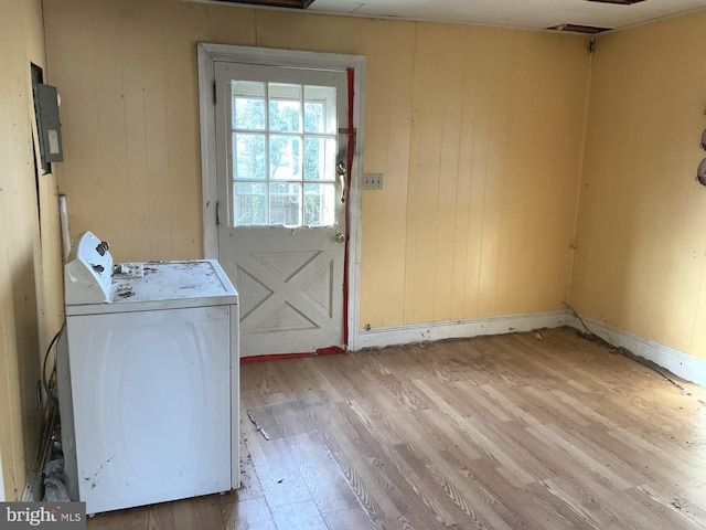 washroom with light wood finished floors, laundry area, washer / dryer, and wooden walls