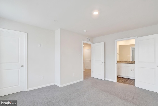 unfurnished bedroom featuring ensuite bath, visible vents, carpet, and baseboards