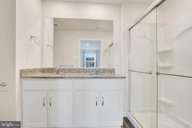 full bath with visible vents, a stall shower, and a sink