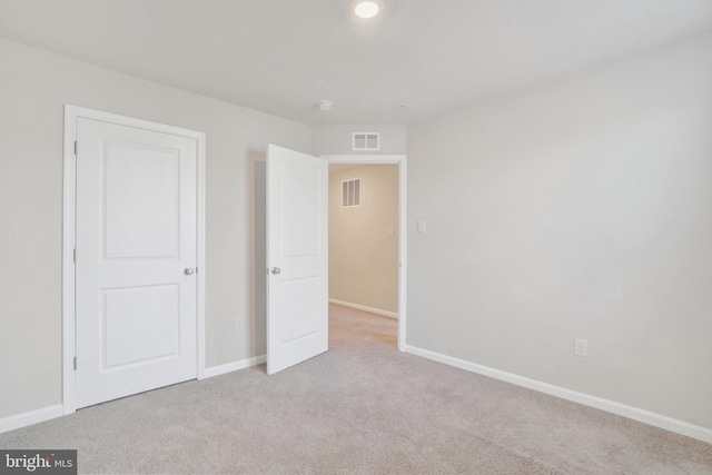 unfurnished bedroom featuring baseboards, visible vents, and light carpet