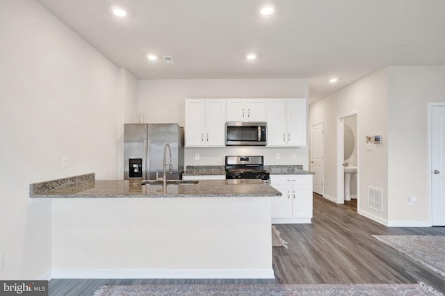 kitchen with white cabinetry, a peninsula, light stone countertops, and stainless steel appliances