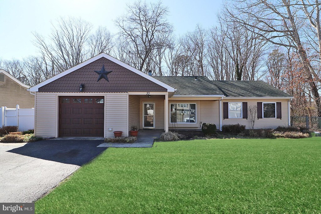 single story home with a front yard, an attached garage, driveway, and fence