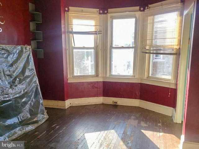 empty room with baseboards and wood-type flooring