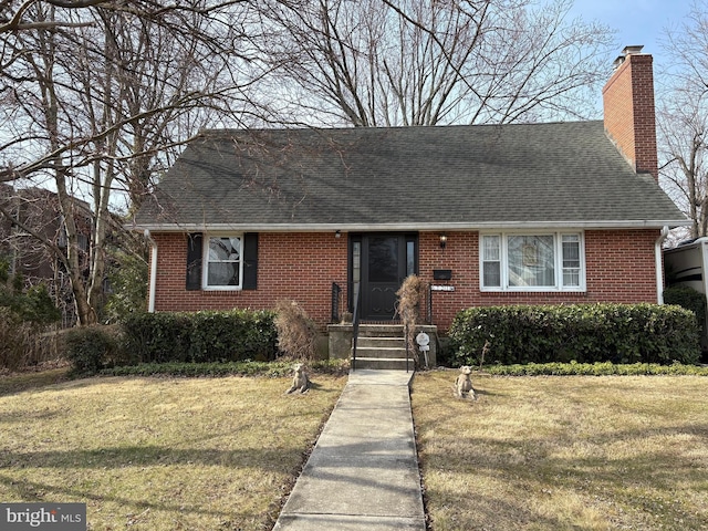 view of front of home with brick siding, a chimney, a shingled roof, and a front yard