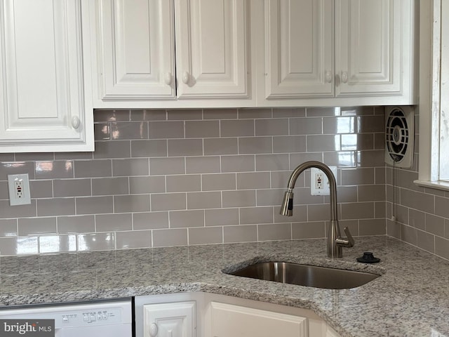 kitchen with backsplash, white cabinetry, white dishwasher, and a sink