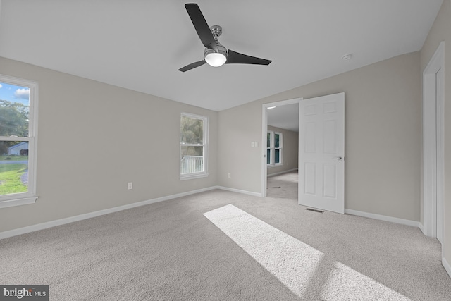 unfurnished bedroom featuring light carpet, visible vents, baseboards, and lofted ceiling