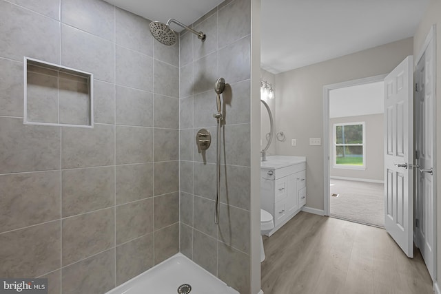 full bathroom featuring tiled shower, wood finished floors, and vanity