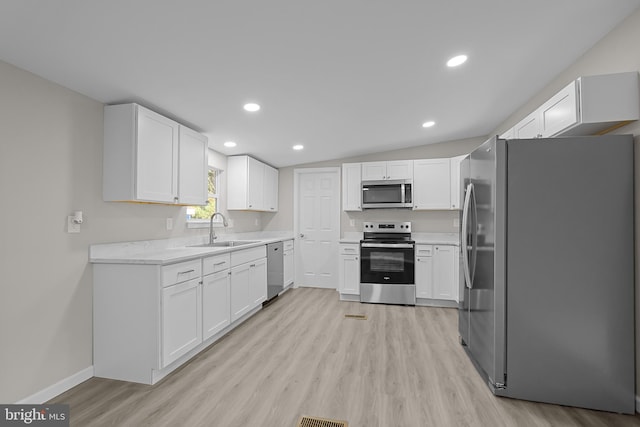 kitchen featuring white cabinetry, light wood-type flooring, appliances with stainless steel finishes, and a sink