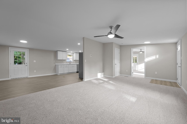 unfurnished living room with recessed lighting, baseboards, and light carpet