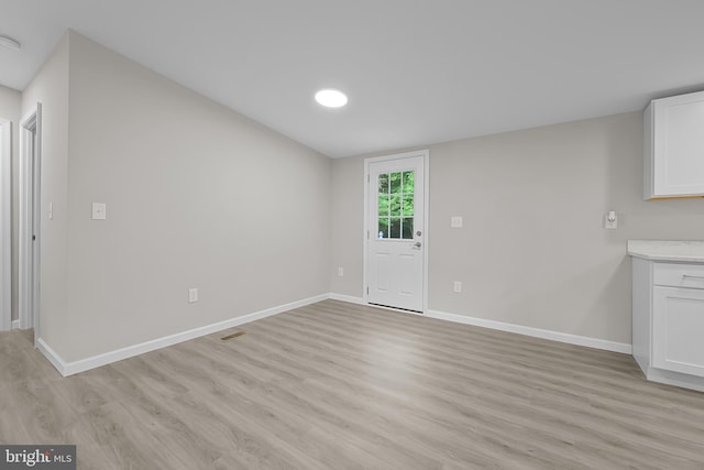 interior space featuring visible vents, light wood-style floors, and baseboards