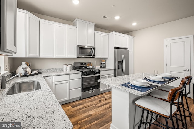 kitchen featuring a breakfast bar, a sink, white cabinetry, recessed lighting, and appliances with stainless steel finishes