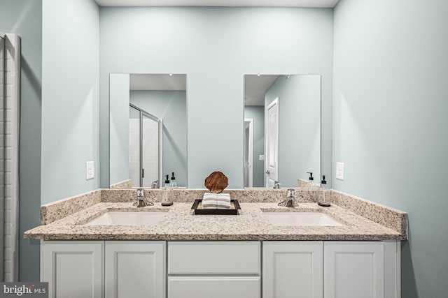 full bath featuring double vanity, a stall shower, and a sink