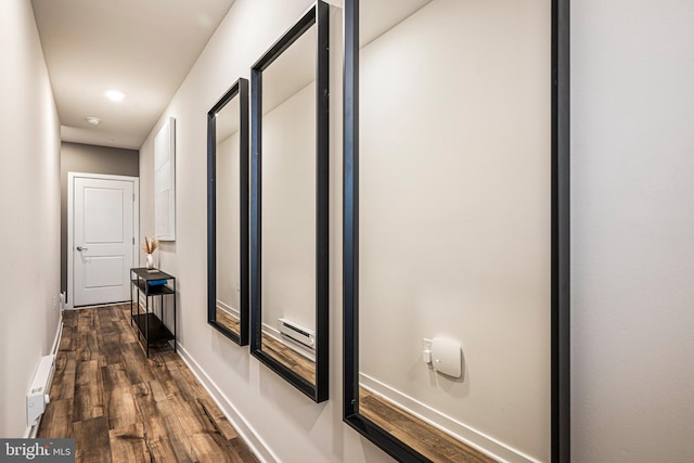 hallway with baseboard heating, a baseboard heating unit, baseboards, and wood finished floors