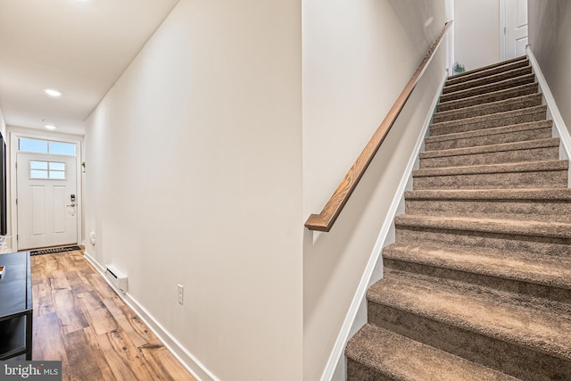 staircase featuring recessed lighting, wood finished floors, baseboards, and baseboard heating