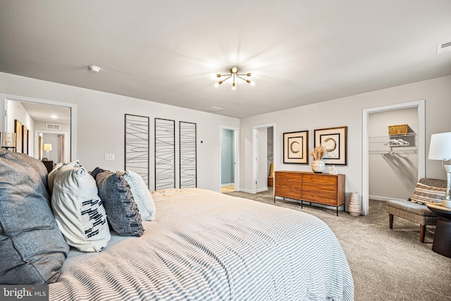 bedroom with visible vents, baseboards, a closet, a walk in closet, and light colored carpet