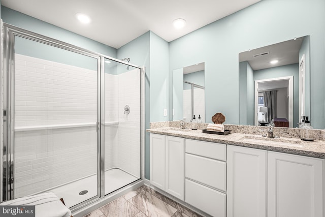 ensuite bathroom featuring double vanity, a stall shower, visible vents, and a sink