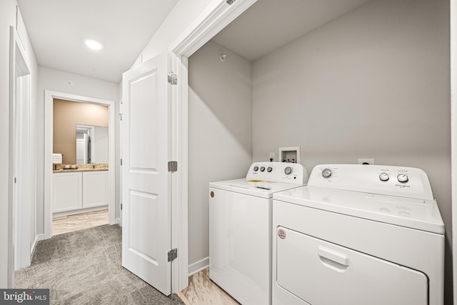 clothes washing area with laundry area, light colored carpet, baseboards, and washing machine and clothes dryer