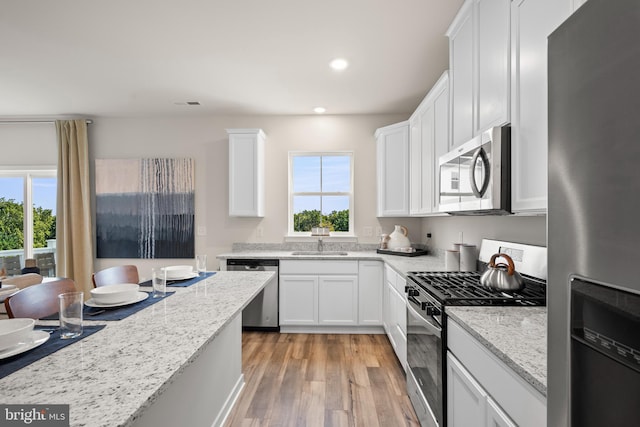 kitchen with light wood-type flooring, light stone counters, white cabinetry, recessed lighting, and appliances with stainless steel finishes