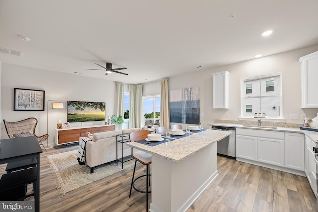 kitchen featuring visible vents, dishwasher, light wood-style flooring, and white cabinetry