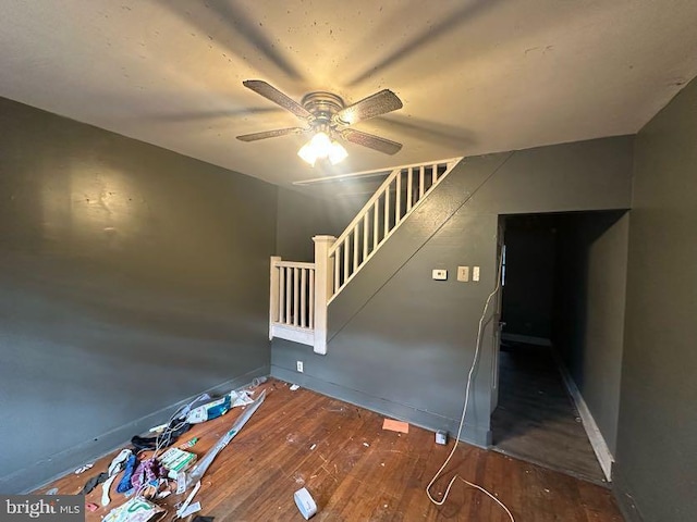 stairway featuring baseboards, ceiling fan, and hardwood / wood-style flooring