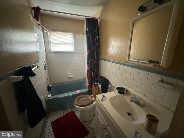 bathroom with a wainscoted wall, toilet, vanity, shower / bath combo, and tile walls