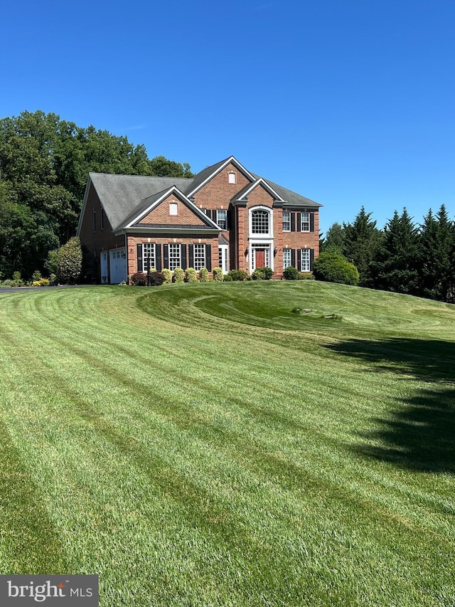 view of front of house with brick siding, an attached garage, and a front lawn