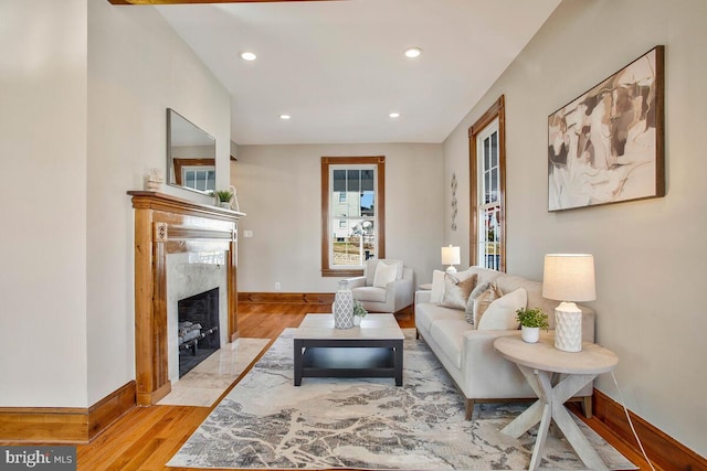 living area with recessed lighting, light wood-type flooring, baseboards, and a premium fireplace