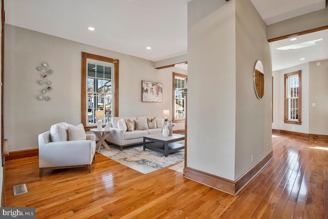 living area with light wood-type flooring, visible vents, baseboards, and recessed lighting