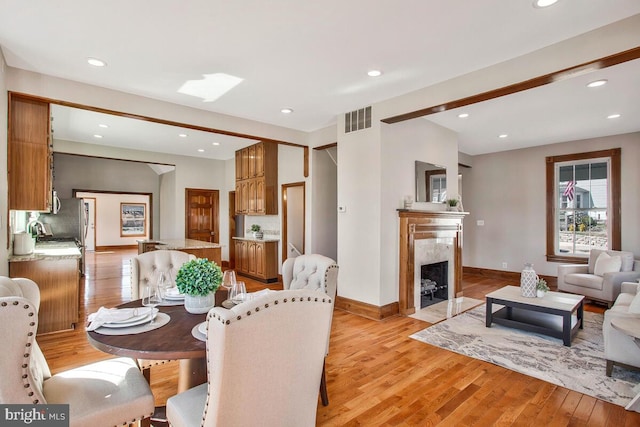 dining area featuring visible vents, a high end fireplace, recessed lighting, light wood-style floors, and baseboards