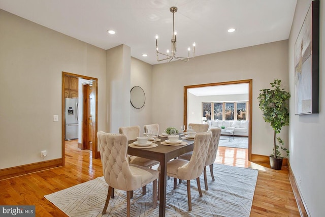 dining space featuring light wood finished floors, recessed lighting, baseboards, and an inviting chandelier