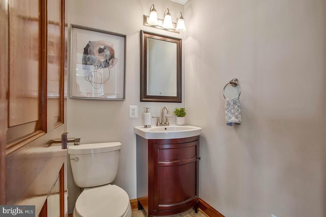 bathroom with toilet, vanity, and baseboards