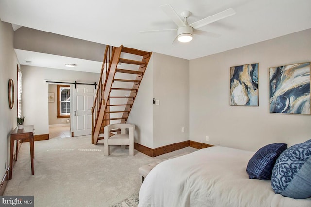 carpeted bedroom with a barn door, baseboards, and ceiling fan