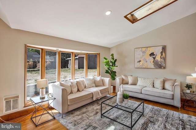 living room featuring recessed lighting, visible vents, vaulted ceiling with skylight, and wood finished floors