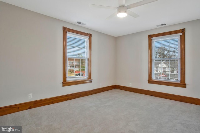 empty room featuring visible vents, a healthy amount of sunlight, and carpet floors