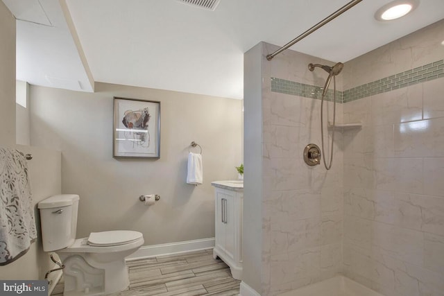 bathroom with vanity, baseboards, wood tiled floor, tiled shower, and toilet