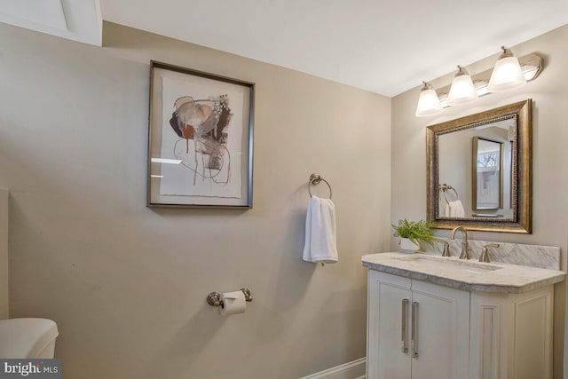 bathroom featuring vanity, toilet, and baseboards