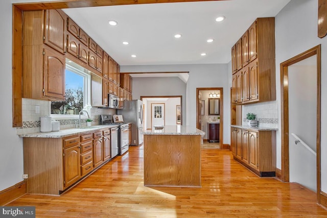 kitchen with light wood-style flooring, brown cabinets, appliances with stainless steel finishes, and a center island