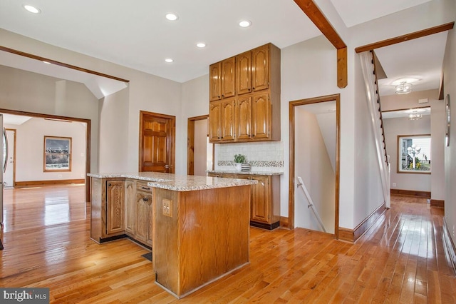 kitchen with decorative backsplash, light wood-style floors, baseboards, and a kitchen island