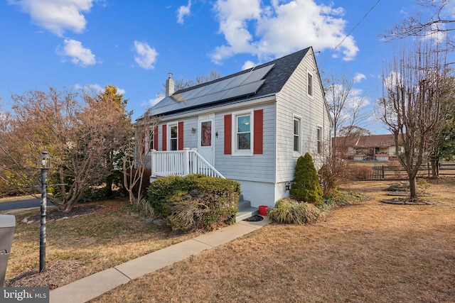 bungalow featuring solar panels, a front yard, fence, and roof with shingles