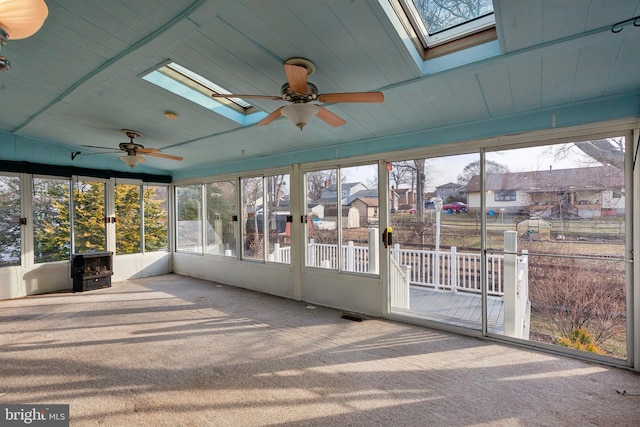 unfurnished sunroom featuring ceiling fan, a residential view, wood ceiling, and a skylight