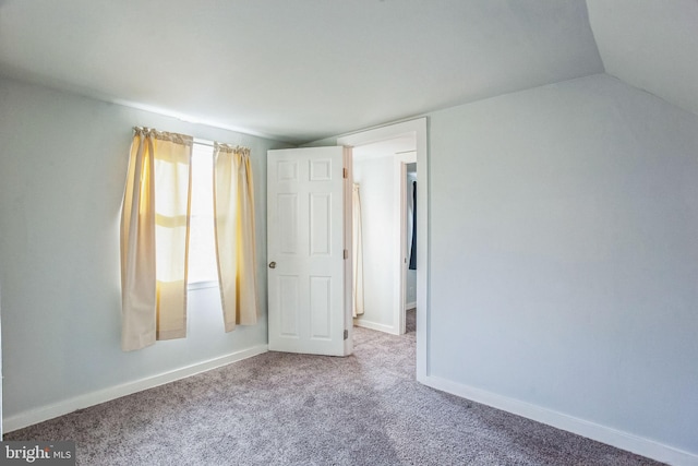 unfurnished bedroom featuring baseboards, lofted ceiling, and carpet flooring