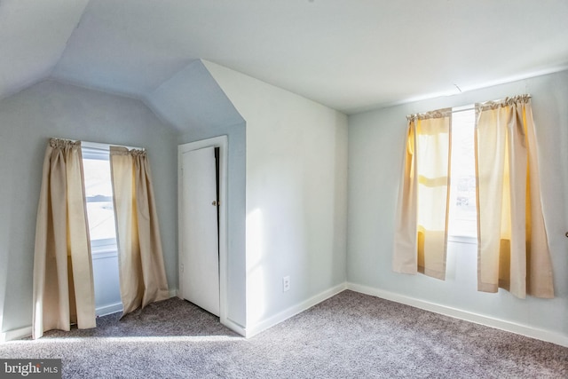 unfurnished bedroom with baseboards, lofted ceiling, and carpet floors