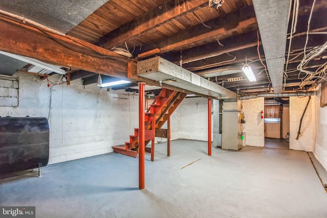 unfinished basement with heating unit, stairway, and heating fuel