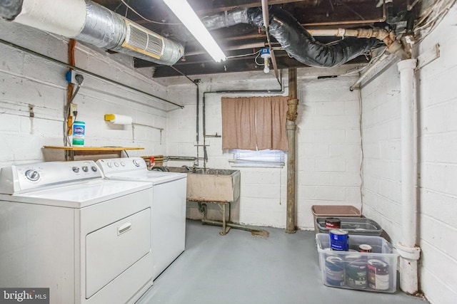 unfinished below grade area with washer and dryer, visible vents, concrete block wall, and a sink