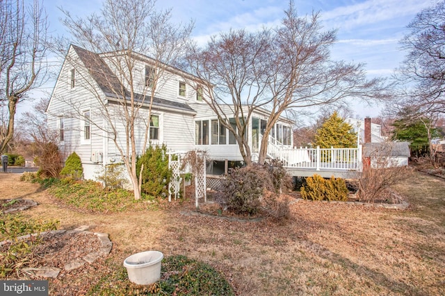 rear view of house with a wooden deck and a sunroom