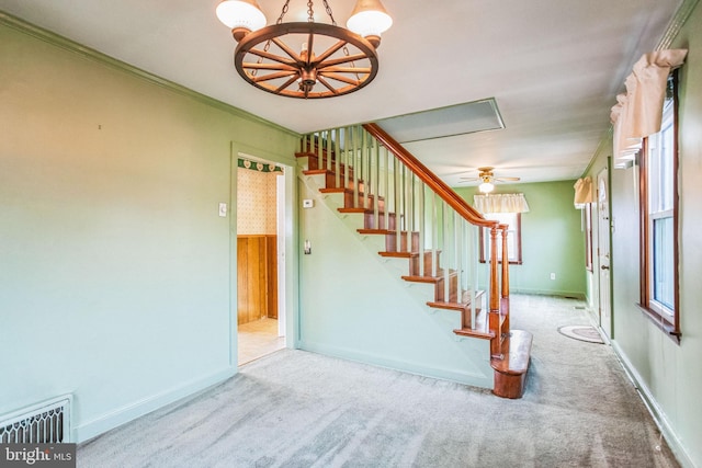 staircase with a notable chandelier, carpet flooring, crown molding, and visible vents