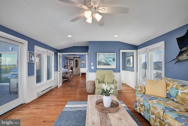 living area with baseboard heating, wood finished floors, lofted ceiling, and a wainscoted wall