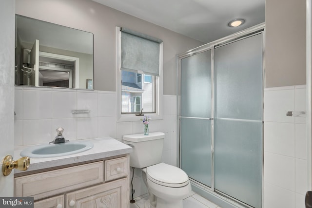 bathroom with vanity, tile walls, toilet, and a stall shower